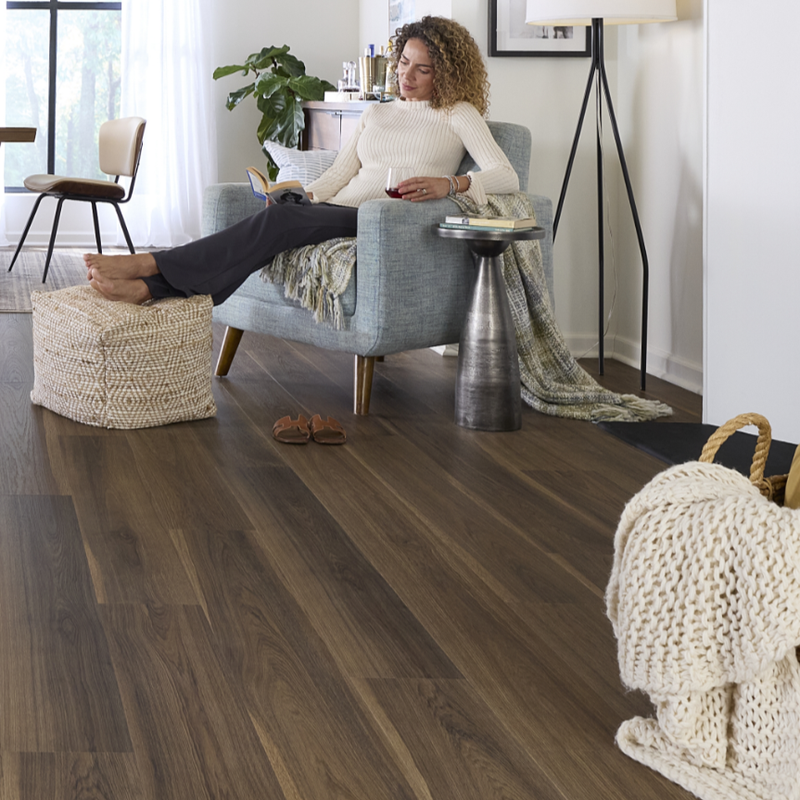 Woman sitting in a living room with dark Pergo flooring